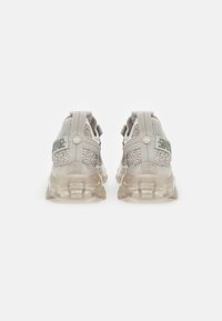 Hellgraue Sneaker mit transparenten Sohle, Mesh-Details und dekorativen Akzenten. Verfügt über Zuglaschen und ein auffälliges Logo an der Seite.