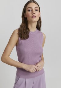 Lila ärmhållen stickad topp med ribbad textur, rund halsringning och figursydd design. Matchas med byxor i en liknande nyans.