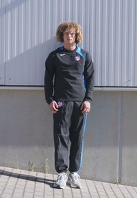 Sort atletisk sweatshirt med blå detaljer og et logo, parret med sorte bukser med blå striber og grå træningssko.