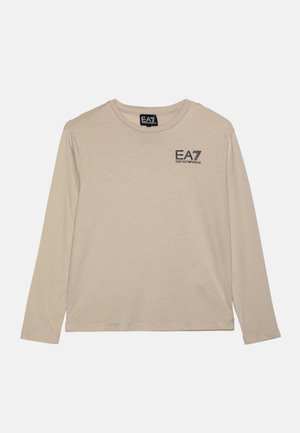 Beige langærmet skjorte med rund halsudskæring og sort EA7 Emporio Armani-logo på øverste venstre bryst mod en ensfarvet baggrund.