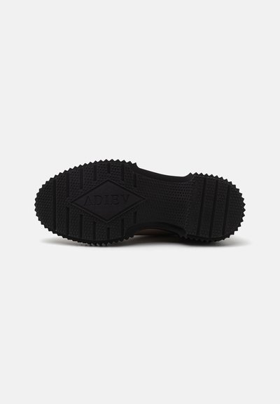 Black rubber shoe sole with textured surface, featuring a diamond-shaped logo and varied tread patterns for grip.