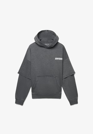 Felpa grigia con taglio boxy, orlo grezzo, tasca frontale e testo "BASIC" in bianco. Presenta maniche corte e un tessuto morbido e testurizzato.