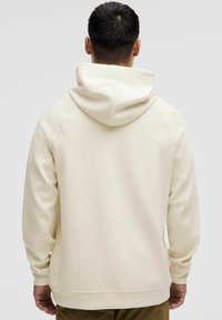 Kremo spalvos hoodie su dideliu gobtuvu, raglan tipo rankovėmis ir gumuotais rankogaliais. Išsiskiria lygiu paviršiumi ir minimalistiniu dizainu.