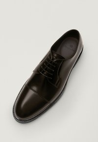 Ruskea nahkakengät, joissa on sileä pinta, nauhakiinnitys ja klassinen muoto. Ominaisuuksiin kuuluu hienovarainen pinta ja pyöreä kärki ohuella pohjalla.