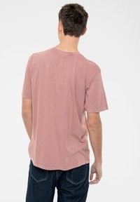 Short-sleeve t-shirt in faded dusty pink, made of soft cotton. Features a crew neck and relaxed fit, with visible stitching details.