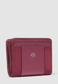 Cartera compacta de cuero burdeos con tarjetero externo y emblema de logo plateado en el bolsillo frontal.