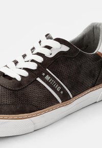 Dark brown suede sneaker featuring white laces, perforated design, gray logo, and white rubber sole with brown accent stitching.