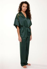 Donkergroene satijnen pyjama set met een kimono-stijl top met kantaccenten, wijde mouwen en bijpassende broek met een strik taille.