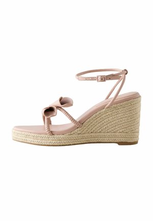 Beige wedge sandal with braided rope heel, ankle strap with buckle, and front straps featuring a decorative bow detail.