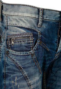 Blaue Jeans aus Denim mit einem verblassten Muster, schrägen Nähten, kontrastierenden Nähten und einer kleinen Reißverschlusstasche auf der Vorderseite.