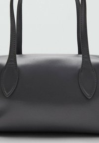 Borsa in pelle nera con due manici allungati, superficie liscia, forma arrotondata e design minimale. Cuciture lungo i bordi.