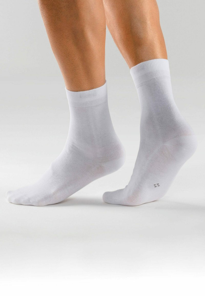 Weiße knöchellange Socken aus glattem Stoff mit gerippten Bündchen, versehen mit verstärkten Fersen und Zehen für zusätzliche Haltbarkeit.