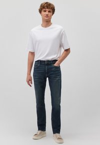 Weißes Baumwoll-T-Shirt, dunkelblaue Jeans, beige Sneaker. Gerader Schnitt, schlichtes Design mit klassischem Schnitt, verfügt über Seitentaschen.