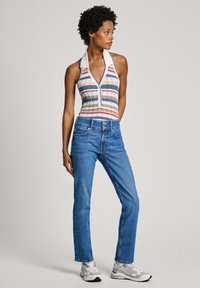 Randig halterneck bodysuit i flerfärgad tyg med knapplist, i kombination med blå raka jeans och vita sneakers.