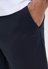 Pantalones cortos deportivos negros con una textura suave, que cuentan con bolsillos laterales y un detalle de costura visible cerca de la cintura.