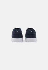 Navy skórzane sneakersy Puma z białą gumową podeszwą. Projekt obejmuje wyściełany kołnierz wokół kostki oraz charakterystyczne logo na pięcie.