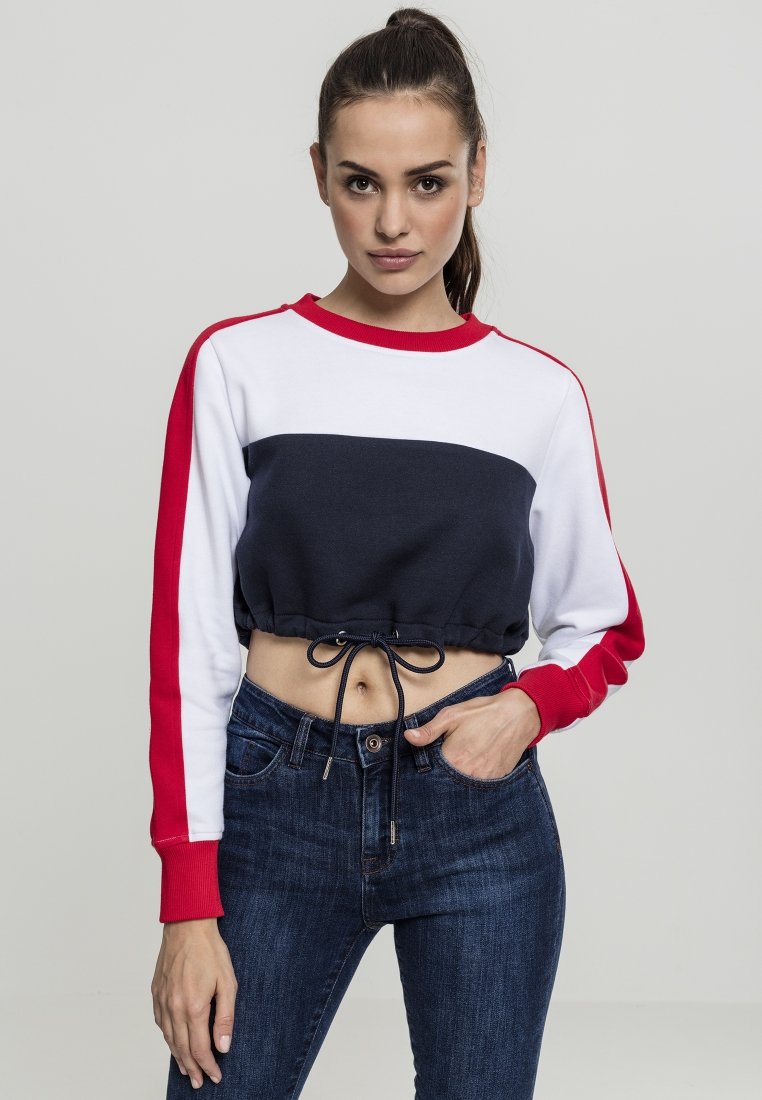 Felpa cropped con design a blocchi di colore blu navy, bianco e rosso. Presenta un cordoncino in vita e polsini a coste. Abbinata a jeans in denim scuro.