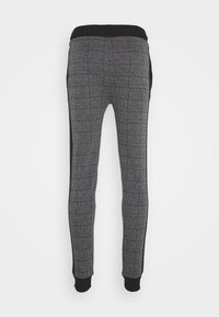 Grå mönstrade joggers med ett texturerat tyg, svarta sidopaneler och ett elastiskt midjeband. Slimmade muddar vid anklarna kompletterar designen.