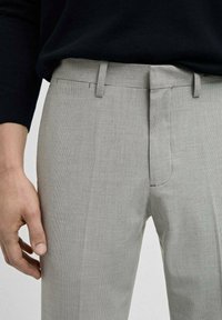 Svijetlosivi hlače od teksturiranog materijala, sa slim fit krojem, pojasom s izrezom i ravnim prednjim dijelom s bočnim džepovima.