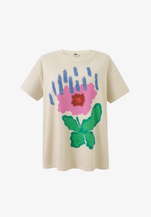T-shirt beige à manches courtes avec une grande fleur rose, des feuilles vertes et des accents de coups de pinceau bleus verticaux sur le devant.