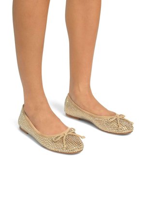 Ballerine beige con punta tonda, decorate con strass trasparenti lungo la parte superiore, dotate di un fiocco in pizzo davanti.