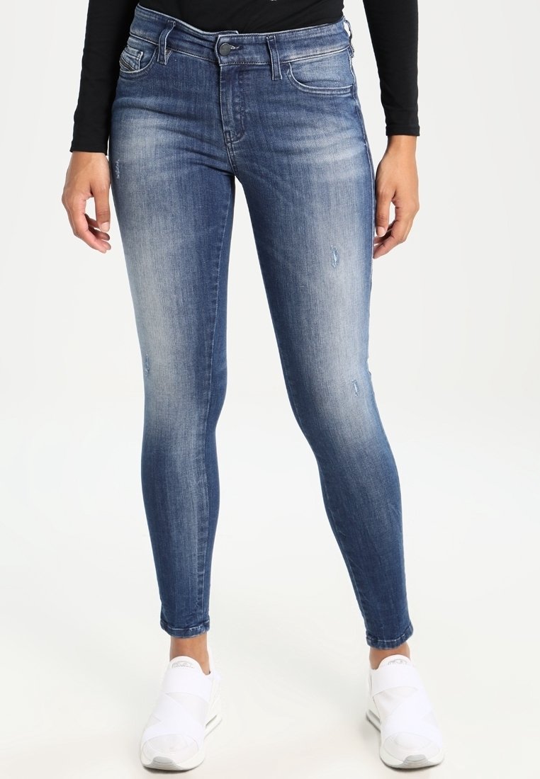 Skinny denim jeans in a medium blue wash, featuring distressed details and subtle fading. Mid-rise waist with a classic five-pocket design.