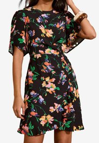 Svart blommig klänning med korta ärmar och insvängd midja, prydd med färgglada, livfulla blommönster och en utställd nederkant.