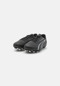 Scarpe da calcio nere in materiale sintetico, con un design elegante, dettagli bianchi e tacchetti moldati per una migliore trazione.