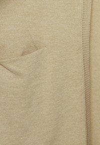 Pull en tricot beige avec un tissu texturé, des poignets côtelés et une poche insérée. Matériau doux et léger avec une finition lisse.
