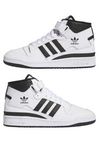 Hvide høje sneakers med sorte accenter, der har tre sorte striber og en Velcro-rem. Struktureret læder og gummisål.