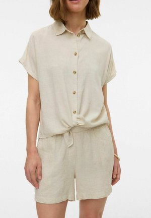 Camisa de manga corta de botón en tono beige claro con un nudo en la parte delantera, combinada con pantalones cortos a juego; hecha de una tela suave y texturizada.