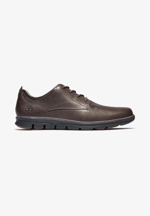 Ciemnobrązowy, skórzany, sportowy but na sznurowadła z czarną gumową podeszwą i logo Timberland wytłoczonym w pobliżu pięty, pokazany w profilu bocznym.