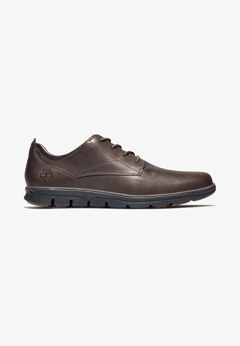 Chaussure décontractée en cuir marron foncé à lacets avec semelle en caoutchouc noir et logo Timberland en relief près du talon, vue de profil latéral.