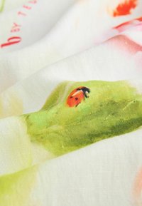 Kangaste sall, millel on valge taust koos lillede ja roheliste lehtede mustritega, millele on lisatud oranži tooni ja lepatriinu illustratsioon. Tekstuuritud kude.