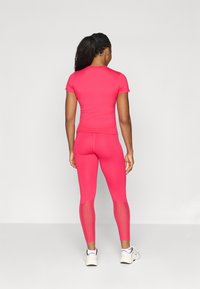 Tettsittende rosa topp med korte ermer, matchende rosa leggings med meshdetaljer. Glatt, elastisk stoff; atletisk design.