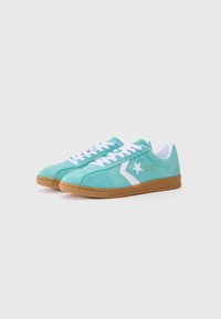 Turkise ruskind sneakers med hvide detaljer, der har et stjernelogo, hvide snørebånd og en tan gummisål. Rund tådesign.