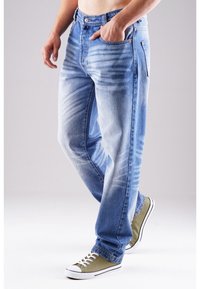 Jasnoniebieskie jeansy z denimu z delikatnym przetarciem, prostym krojem, pięcioma kieszeniami i metalowymi detalami. Zestawione z zielonymi niskimi trampkami.