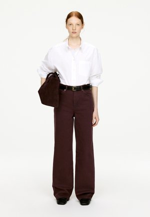 Weißes Hemd mit Knopfverschluss, lockere Passform; burgunderrote weite Hose; schwarzer Gürtel; braune Wildleder-Handtasche; glatte Textur und klare Linien.