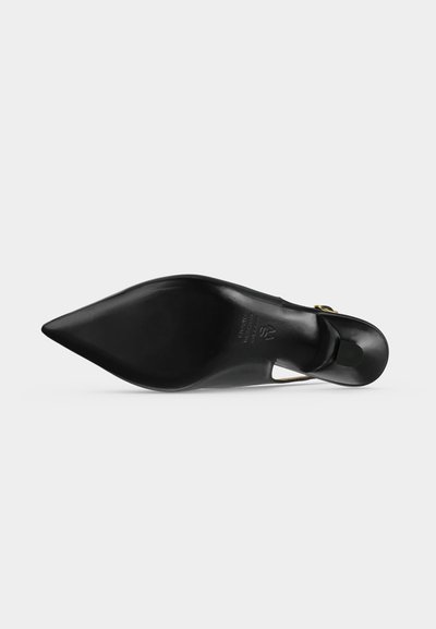 Chaussure à talon haut noire à bout pointu vue de la semelle, avec une texture lisse et une boucle dorée près du talon.