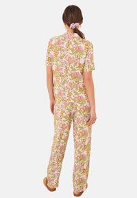 Set di abbigliamento da casa con motivo floreale in tessuto morbido, composto da una maglietta a maniche corte e pantaloni larghi. I colori includono rosa, verde e beige.