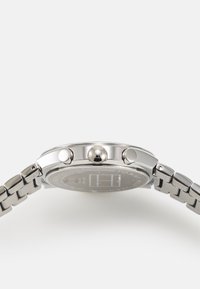 Silberner Edelstahlchronograph mit rundem Gehäuse, drei Drückern und strukturiertem Zifferblatt, ausgestattet mit einem Gliederarmband und Markendetails.