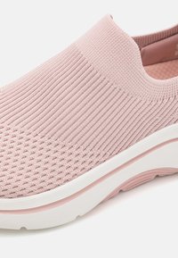 Zapato de punta rosa tipo slip-on con parte superior de punto texturizado, diseño de malla y suela de goma blanca. Cuenta con un collar acolchado y un forro interior suave.