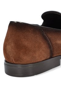 Brązowy zamszowy but z teksturowaną powierzchnią i zaokrąglonym obcasem. Posiada czarną lamówkę wzdłuż otwarcia oraz wzorzystą gumową podeszwę.