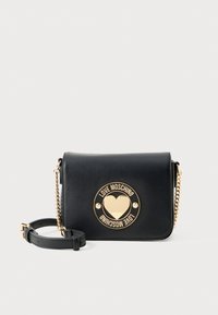 Borsa a tracolla in pelle nera con hardware dorato, logo circolare con dettaglio a forma di cuore, tracolla a catena regolabile, forma rettangolare.
