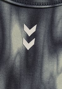 Deux flèches blanches en forme de chevrons pointant vers le bas sur un tissu texturé foncé, centrées sous la couture du col.