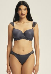 Czarny szary biustonosz i pasujące majtki ozdobione koronką. Biustonosz ma wyprofilowane miseczki i falbankowe koronkowe ramiączka. Gładka tekstura na całej powierzchni.