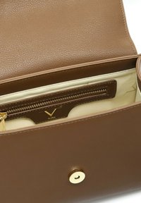 Interno di una borsa in pelle marrone, con una tasca con zip dotata di hardware dorato e una fodera marrone texturizzata. La chiusura è a scatto dorato.