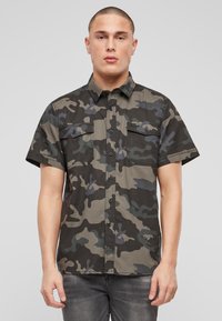 Krátky rukáv, maskáčová košeľa v odtieňoch zelenej, čiernej a modrej; má dve náprsné vrecká a zapínanie na gombíky; materiál z bavlneného zmesi.