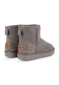 Botas de tobillo de ante gris con un interior suave, que presentan una suela de goma plana y un pequeño logo rectangular en el talón trasero.