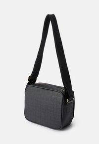 Czarna prostokątna torebka typu crossbody wykonana z teksturowanego materiału, z delikatnym wzorem logo, złotymi akcentami oraz szerokim materiałowym paskiem.